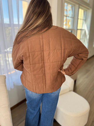 Person wearing a brown quilted jacket in a living room setting