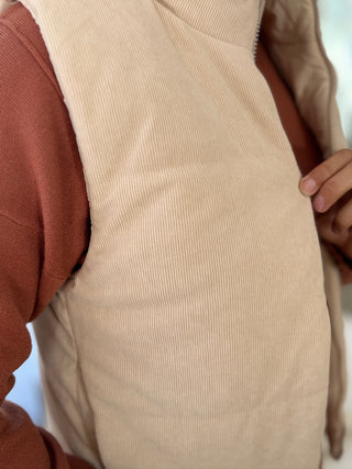 Close-up of a beige corduroy vest worn over a brown shirt.