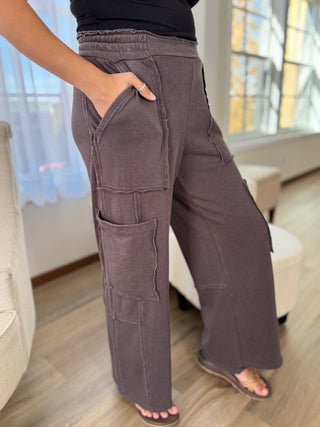 Person wearing brown cargo pants in a room with a window in the background