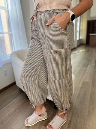 Person wearing striped pants in a room with a window and furniture.
