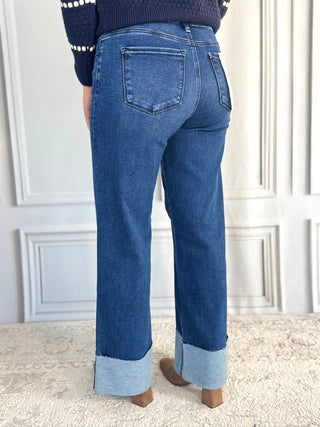 Person wearing blue jeans with a white wall background