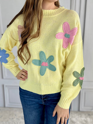 Yellow sweater with floral designs worn by a person indoors.