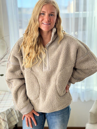 Woman wearing a beige fleece pullover in a home setting