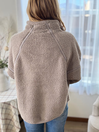 Person wearing a beige fleece jacket in a home setting