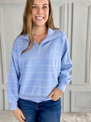 Woman wearing a blue striped hoodie with a neutral background