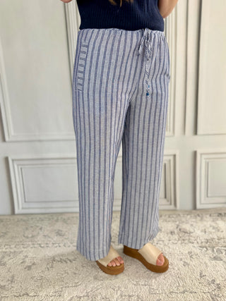 Person wearing blue and white striped pants in a room with light-colored walls and flooring.