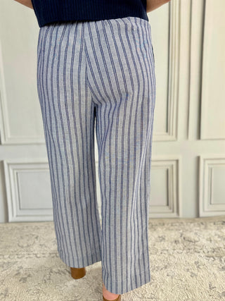 Person wearing blue and white striped pants in a room with a white wall.