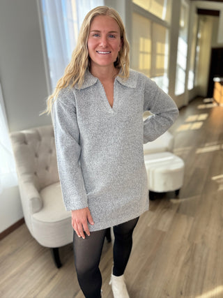 Woman wearing a gray sweater in a room with light-colored furniture.