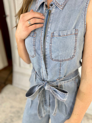 Light blue denim jumpsuit with a tie waist, worn by a person.