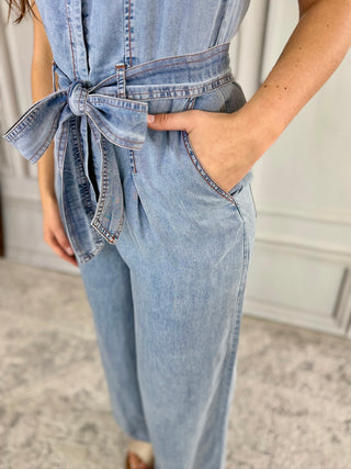 Light blue denim jumpsuit with a tie waist worn by a person.