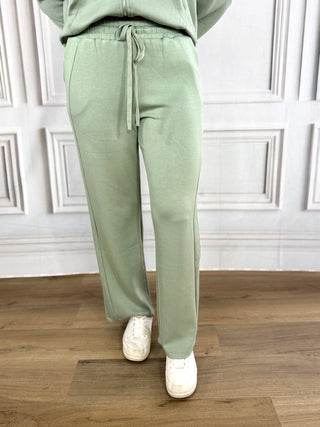 Person wearing light green sweatpants with a white background