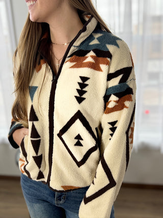 Person wearing a patterned sweater with a blurred indoor background