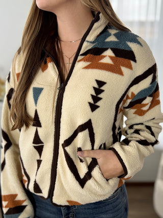 Person wearing a patterned fleece jacket with a neutral background