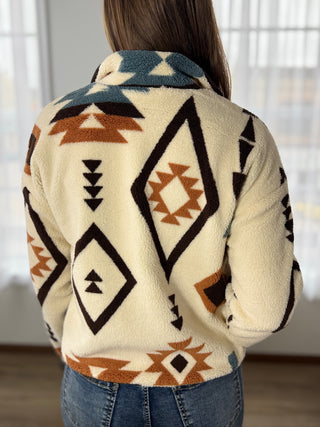 Person wearing a patterned sweater with geometric designs indoors