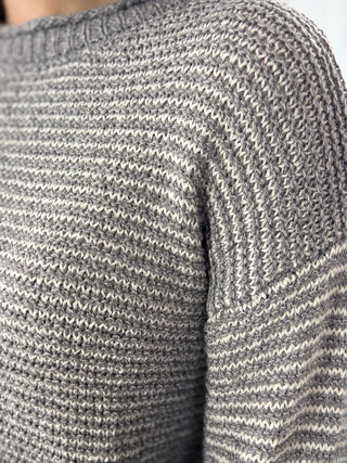 Close-up of a gray and white striped sweater sleeve