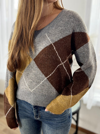 Person wearing a patterned sweater with a neutral background