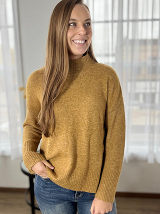 Woman wearing a mustard yellow sweater in a room with neutral decor