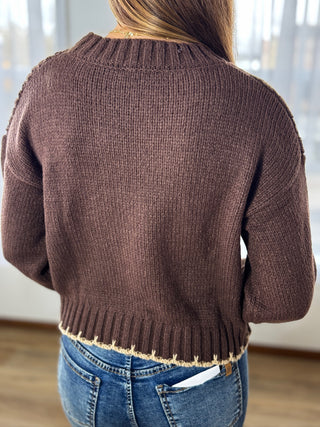Brown knitted sweater worn by a person with a blurred background