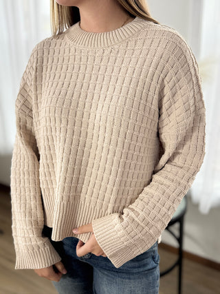 Beige knitted sweater worn by a person with a blurred background