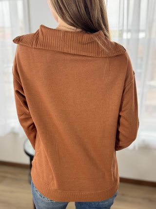 Person wearing a brown sweater with a blurred background