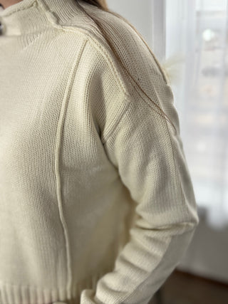 Close-up of a beige sweater with a blurred background