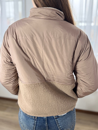 Person wearing a beige quilted jacket with a neutral background