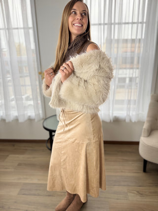 Woman holding a fur stole in a room with large windows