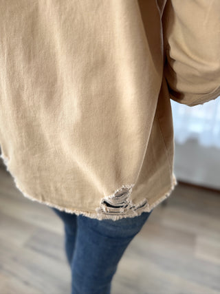 Beige jacket with a ripped design worn by a person indoors.