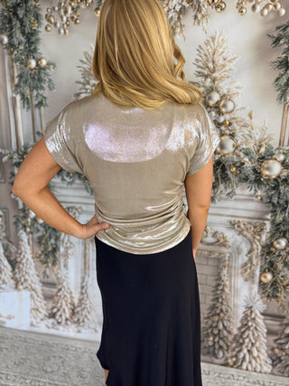 Person wearing a sparkly silver top in a decorated room with Christmas trees.