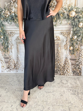 Person wearing a black dress standing in front of a decorative wall with Christmas decorations.