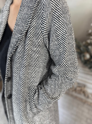 Close-up of a person wearing a black and white herringbone patterned coat.