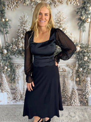 Woman in a black dress standing in front of a decorated Christmas background