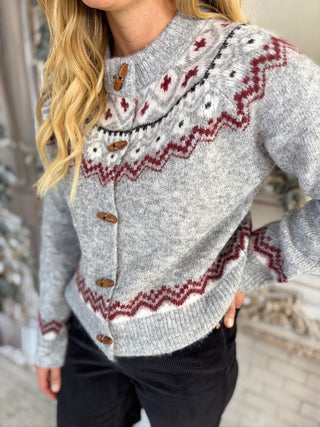 Person wearing a gray sweater with red and white pattern