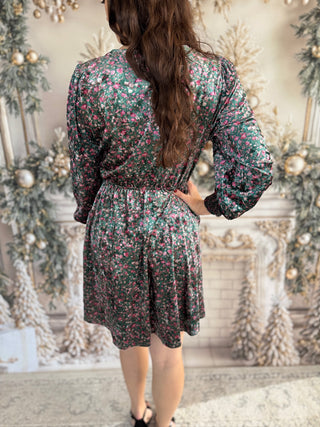 Woman wearing a floral dress in a decorated room with Christmas trees.