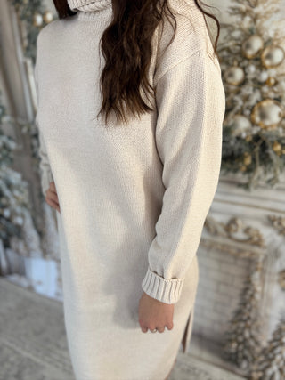 Person wearing a long beige sweater in an ornate room.