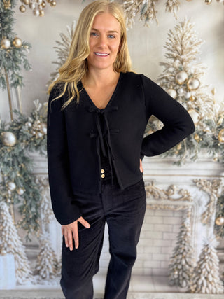 Woman in a black outfit standing in front of a decorated Christmas background