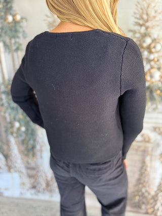 Person wearing a dark gray long-sleeve top and pants with a blurred snowy background