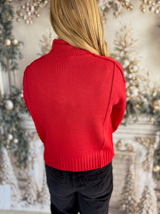 Person wearing a red sweater with a blurred decorative background
