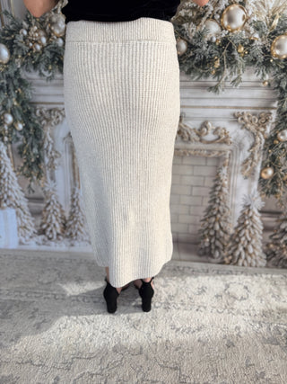 Person wearing a beige ribbed skirt with a decorative Christmas-themed background