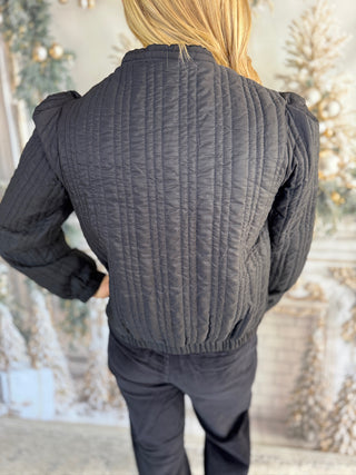 Person wearing a textured gray jacket in front of a decorative background