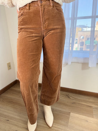Brown corduroy pants worn by a person indoors with a window in the background