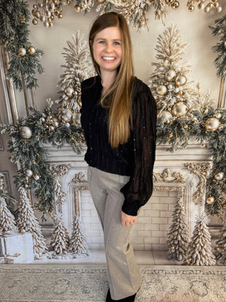 Woman standing in front of a decorated fireplace with Christmas trees and ornaments.