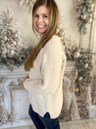 Woman wearing a cream sweater standing in front of a decorated fireplace.