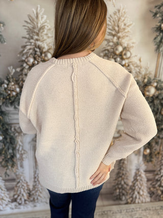 Person wearing a beige sweater with a decorative background