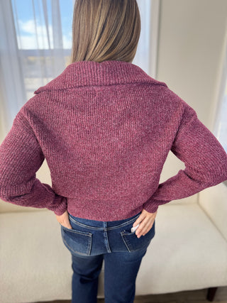 Person wearing a maroon knitted cardigan in a room with a window in the background