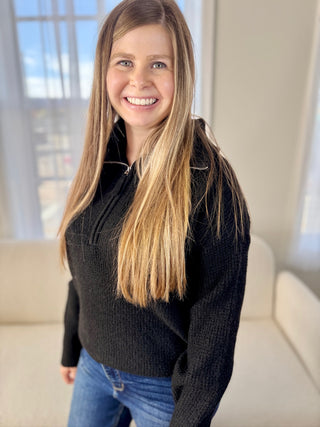 Woman wearing a black sweater and blue jeans indoors