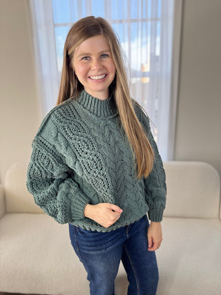 Woman wearing a green cable knit sweater in a living room setting