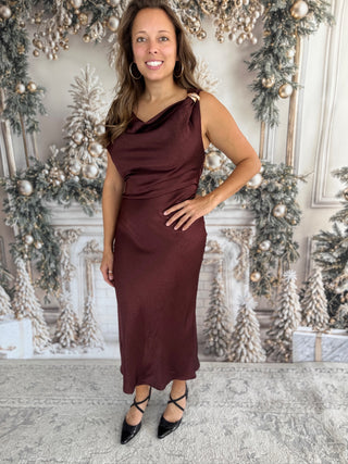 Woman in a burgundy dress standing in front of a decorated Christmas background