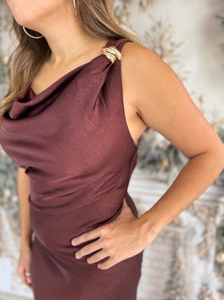 Woman wearing a burgundy one-shoulder dress with a blurred background