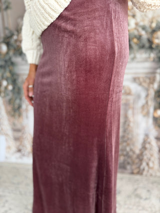 Person wearing a burgundy velvet skirt with a blurred background